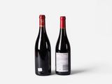 two bottles of red wine sitting next to each other on a white surface