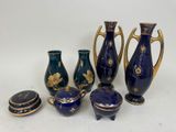 several pieces of blue and gold vases and lids on a white surface