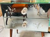 a glass table with three drawers and a painting on it