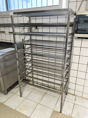 une étagère métallique au milieu d'une cuisine, avec un micro-ondes en arrière-plan