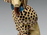 une figurine en céramique représentant un guépard avec un nœud bleu