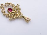 a gold brooch with a red stone in it
