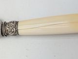 a silver spoon with a white handle on a white table