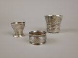 trois tasses en argent posées l'une à côté de l'autre sur une surface blanche