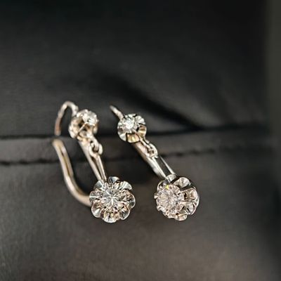 une paire de boucles d'oreilles en diamant posée sur une surface en cuir noir