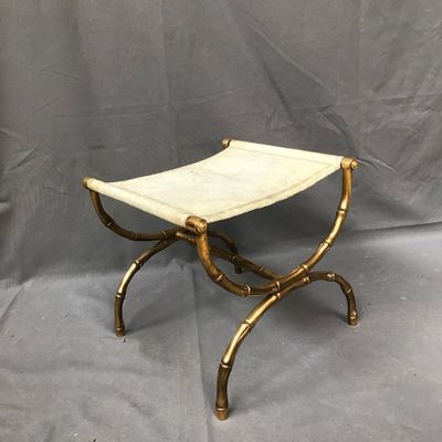 un tabouret doré et blanc sur un fond gris, avec une toile de fond grise