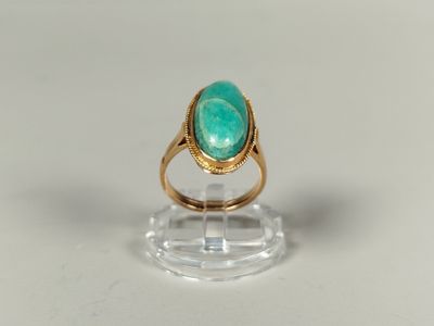 Gros plan sur une bague en or ornée d'une pierre verte