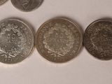 six different types of coins are arranged in a row on a white surface