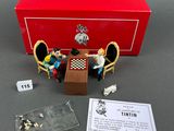 a red box with miniature figurines of people sitting at a table