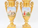 deux vases en or ornés de peintures, posés sur une table