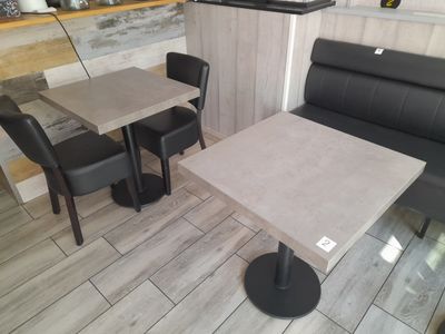 une table et deux chaises noires dans une petite pièce