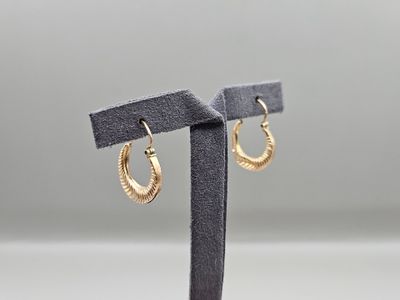 a pair of gold hoop earrings on a black stand