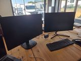 two computer monitors sitting on a table with a keyboard and mouse