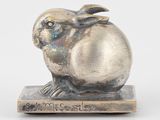 sculpture en argent représentant un lapin assis sur un bloc de bois