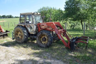 a red tractor that is parked in the grass