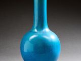 un vase en verre bleu posé sur une table, sur une surface grise