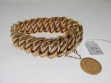a close up of a gold bracelet with a coin on it