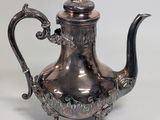 an antique silver teapot with a bird on top of it