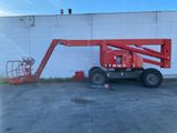 Une nacelle élévatrice rouge est garée devant un bâtiment blanc