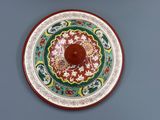 une assiette rouge et verte ornée d'un motif floral