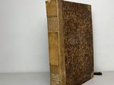 un vieux livre posé sur une table à côté d'un mur blanc