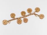 un gros plan d'un bracelet composé de pièces d'or posé sur une surface blanche