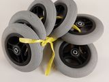 four grey wheels with yellow ribbon tied to them on a white surface