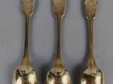 six spoons and a spoon rest on a gray surface