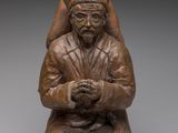 une photo représentant une statue d'un homme assis sur un tabouret