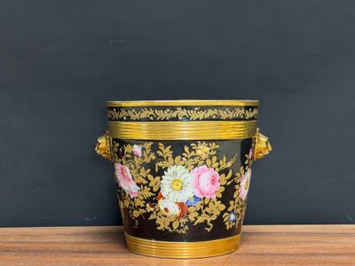 an image of a black and gold vase sitting on top of a wooden table
