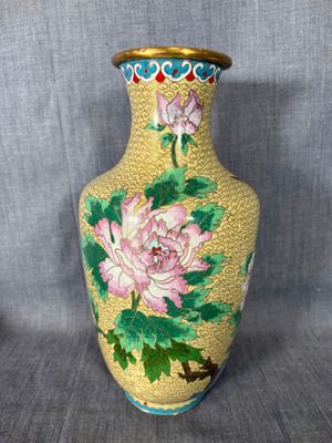 un vase jaune orné de fleurs roses et de feuilles vertes