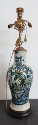 un vase bleu et blanc posé sur une table sur laquelle se trouve une lampe