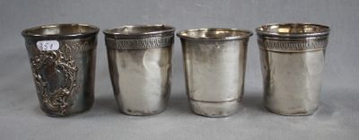 four silver cups are lined up next to each other on a table