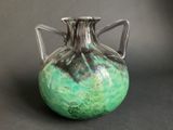 a green and black vase sitting on a table