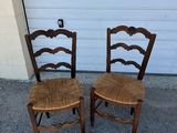 two wooden chairs sitting next to each other in front of a garage door