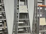 several ladders are lined up in a warehouse with a sign on the floor