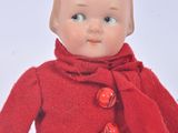 a small doll that is wearing a red coat and scarf