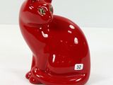 une figurine de chat rouge posée sur une surface blanche