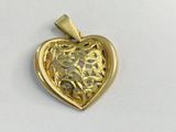une image représentant un pendentif doré en forme de cœur posé sur une surface blanche