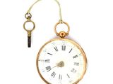 une montre de poche en or à laquelle est accrochée une clé sur le côté