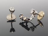 deux paires de boucles d'oreilles en diamant posées sur une surface noire