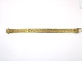 a gold bracelet with writing on it sitting on top of a white surface