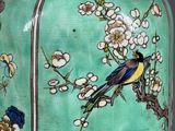 a green vase with birds and flowers painted on it