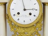 a gold clock with a white face on a stand