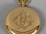 an image of a gold pocket watch with a monogram on the front
