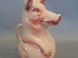 un petit cochon en céramique posé sur une tasse