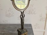 un miroir posé sur une table sur laquelle se trouve une statue