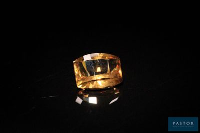 une bague en or posée sur une surface noire, avec un fond noir