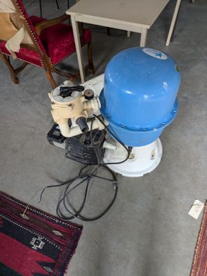 un réservoir d'eau bleu posé par terre à côté d'une chaise rouge