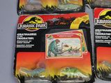 three toy dinosaurs in plastic packaging sitting on a table
